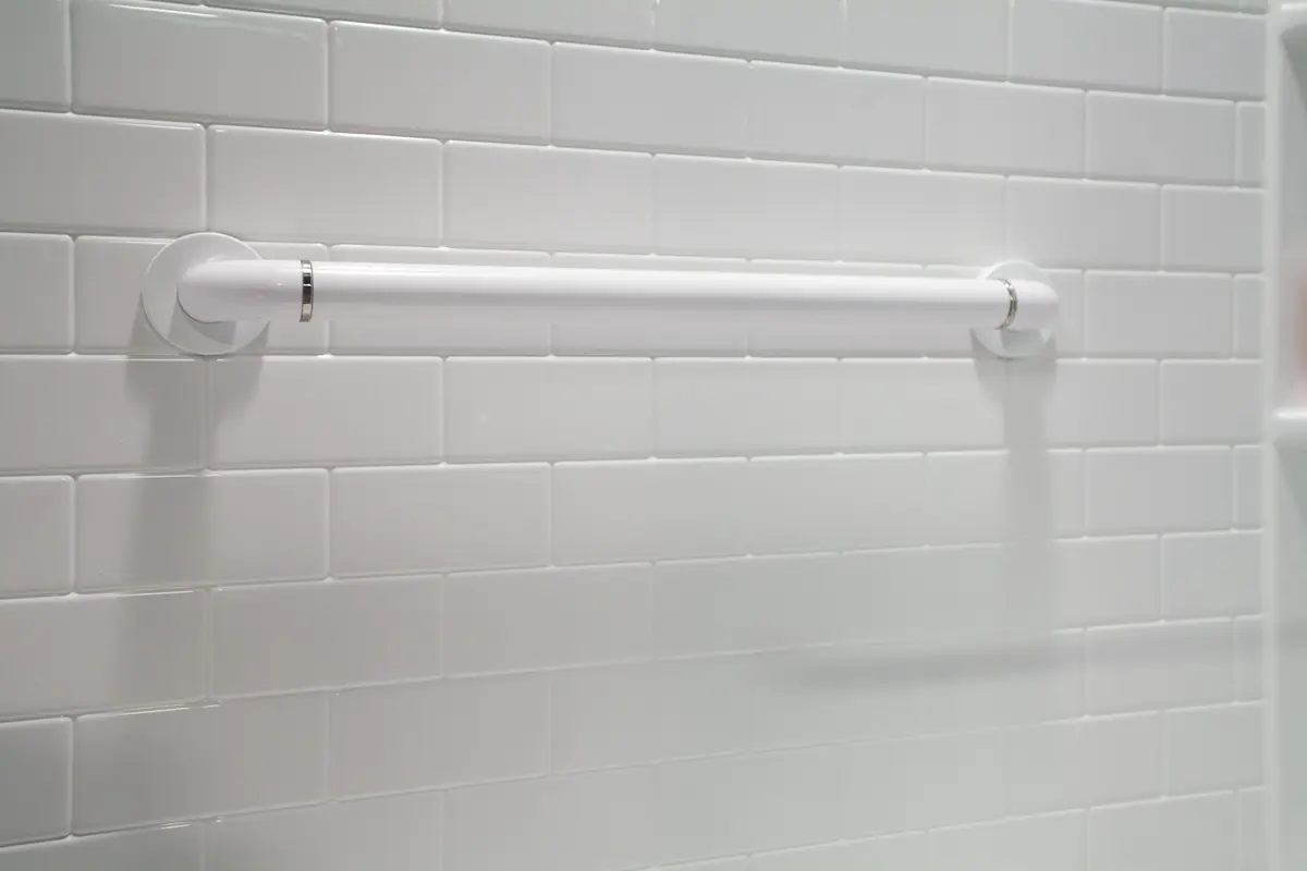 White straight grab bar on white subway tile wall