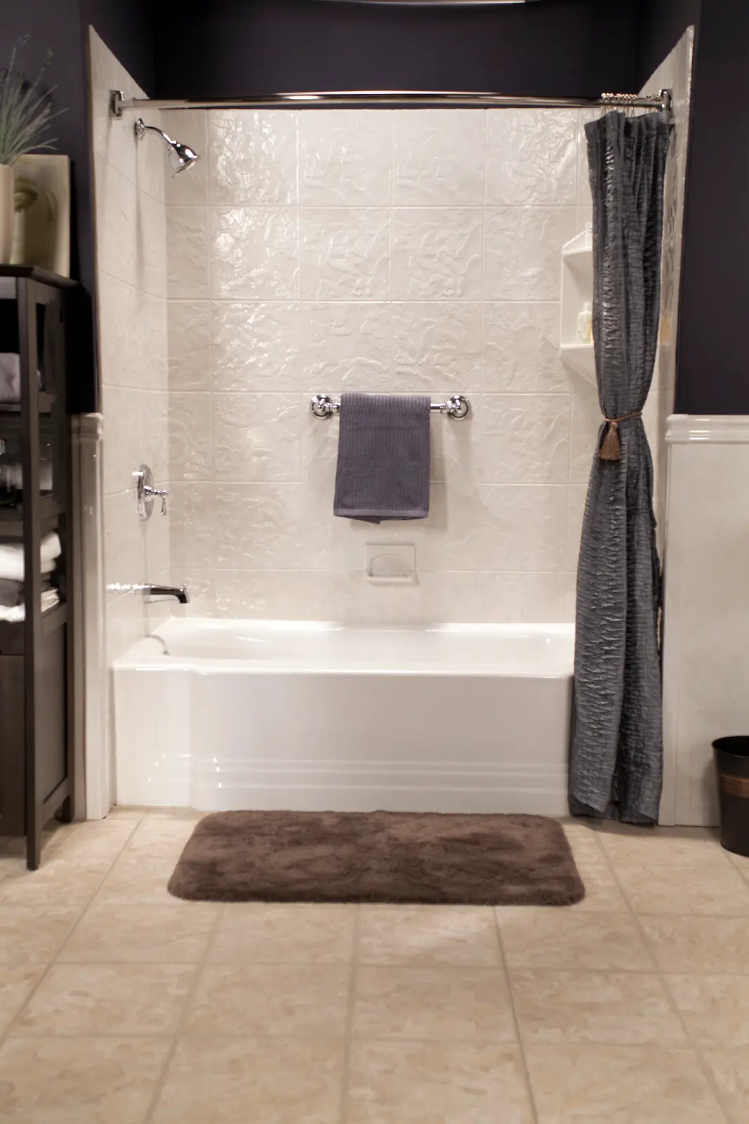 White classic tub with silver white tile walls and polished chrome in dark bathroom