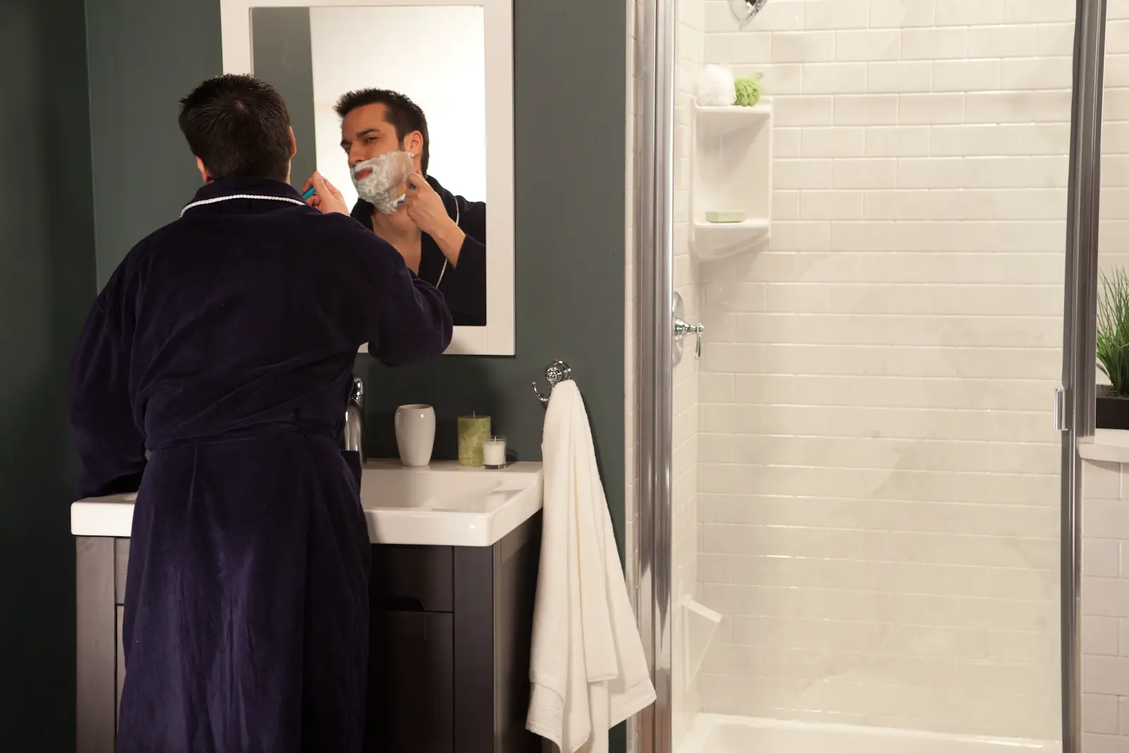 White subway tile shower with glass door in forest green bathroom