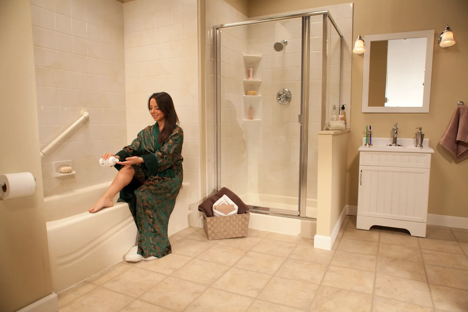 Woman in green robe applying lotion next to almond wave tub and shower with marble walls